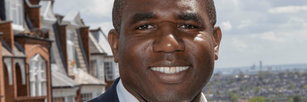 Image of David Lammy stood in front of some houses.